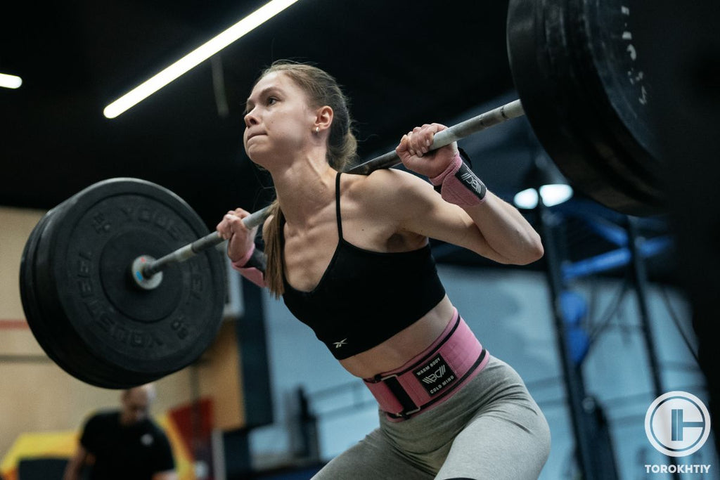 Una mujer haciendo sentadillas traseras con un cinturón de gimnasia