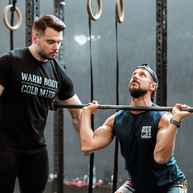 Two men working out with a barbell in a gym setting (TOROKHTIY WEIGHTLIFTING)