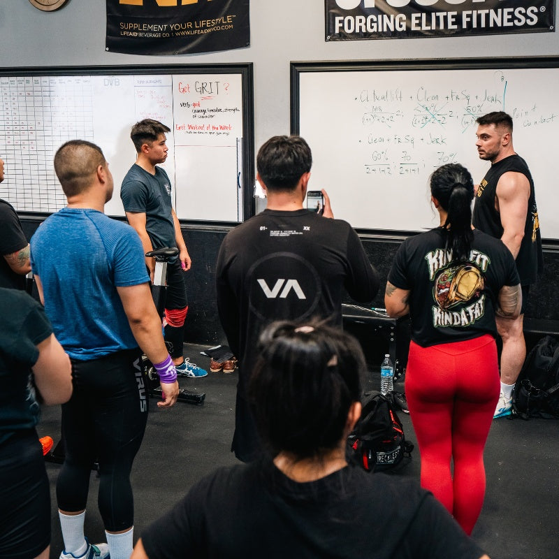 Group of people in a fitness or training facility with whiteboards and motivational posters (Torokhtiy Weightlifting)