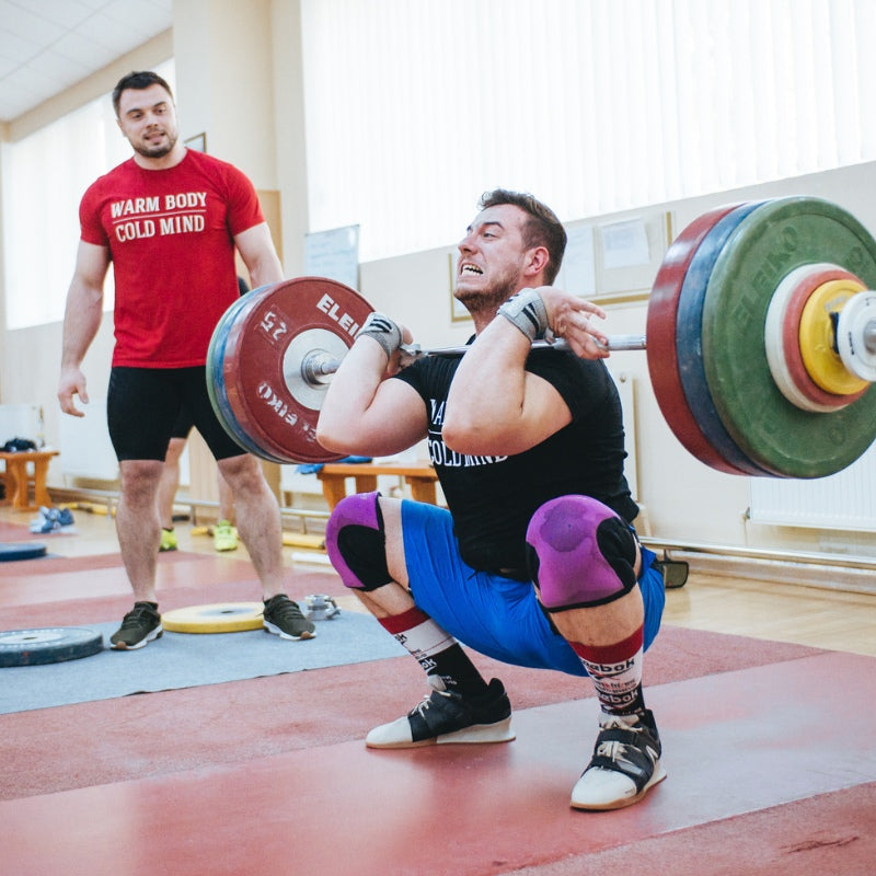 Person lifting weights with a spotter in a gym setting (Torokhtiy Weightlifting)