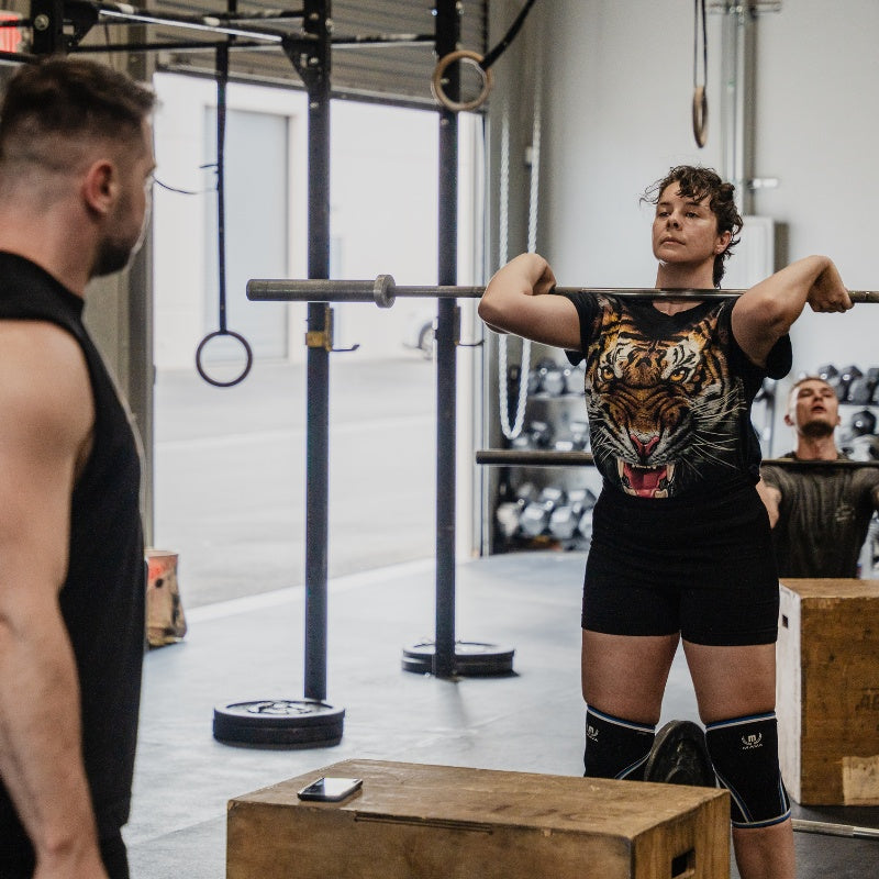 Person lifting a barbell in a gym setting with another person observing  (Torokhtiy Weightlifting)