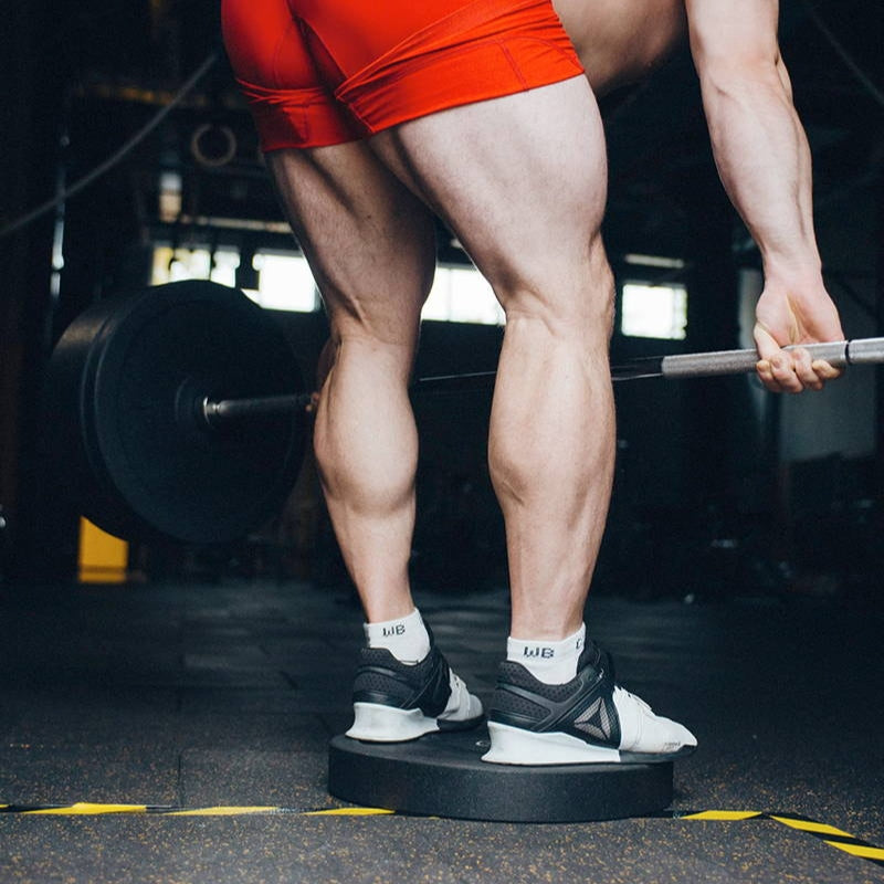 Person lifting a barbell with focus on legs and feet in a gym setting (Torokhtiy Weightlifting)