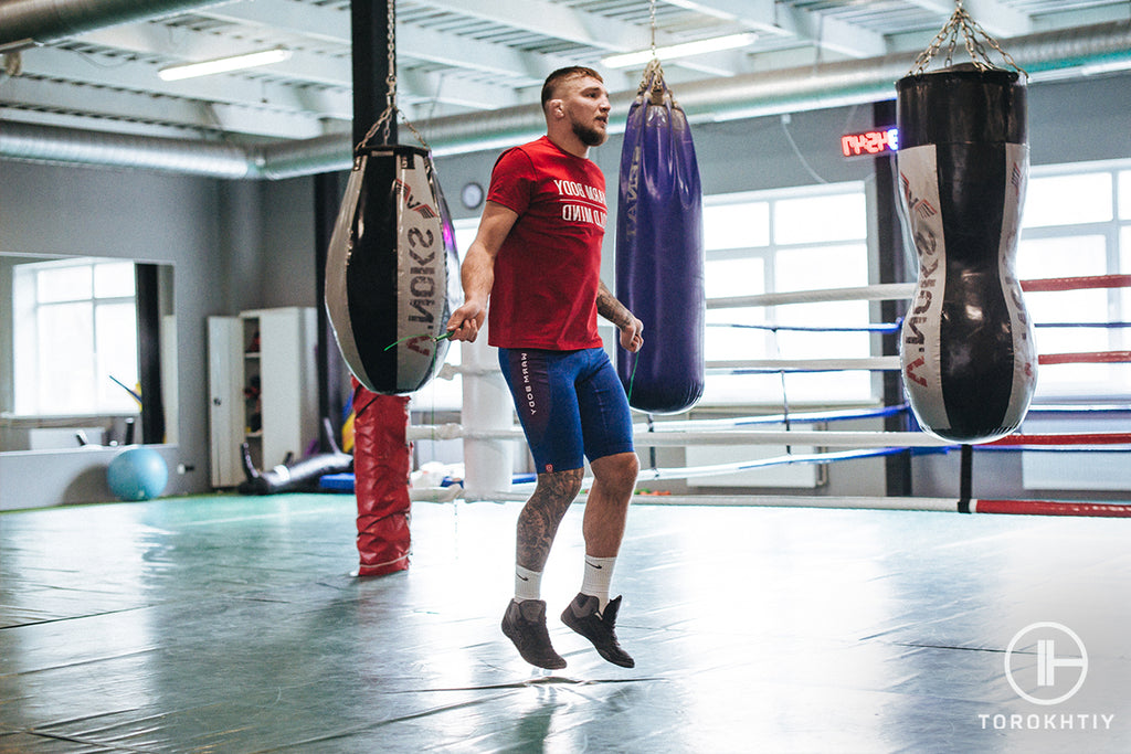 Un hombre haciendo ejercicio con una cuerda para saltar en un gimnasio de boxeo