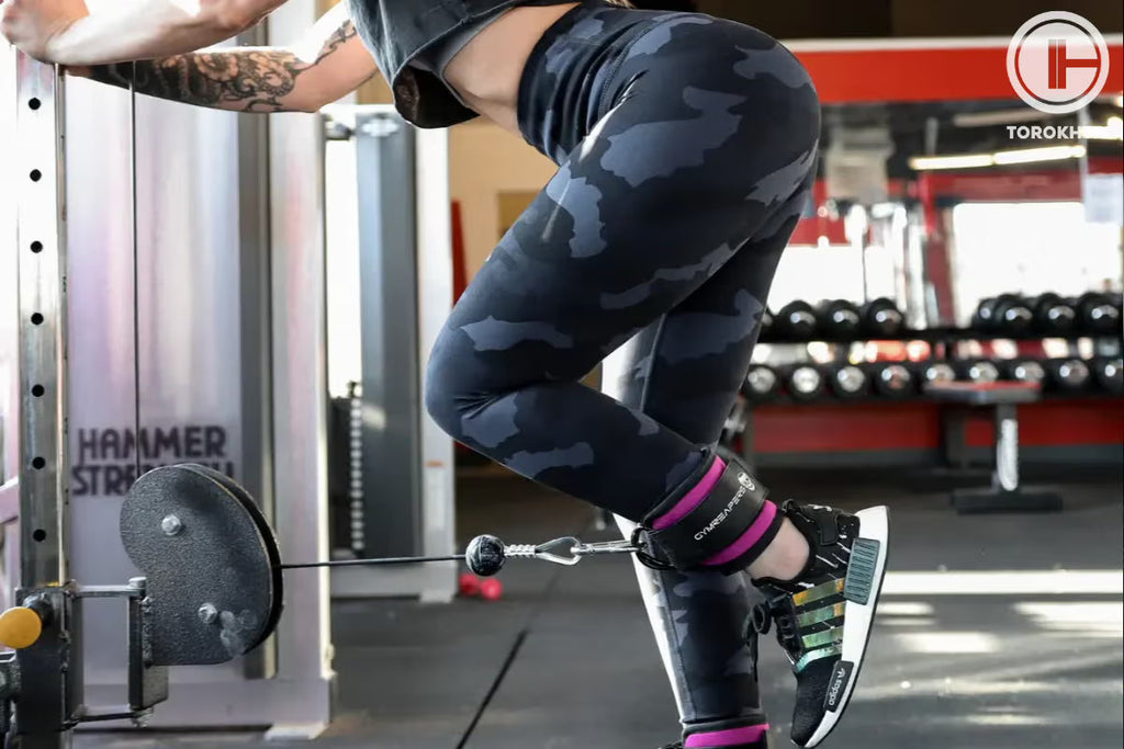 Person lifting weights in a gym setting with 'Hammer Strength' equipment visible.
