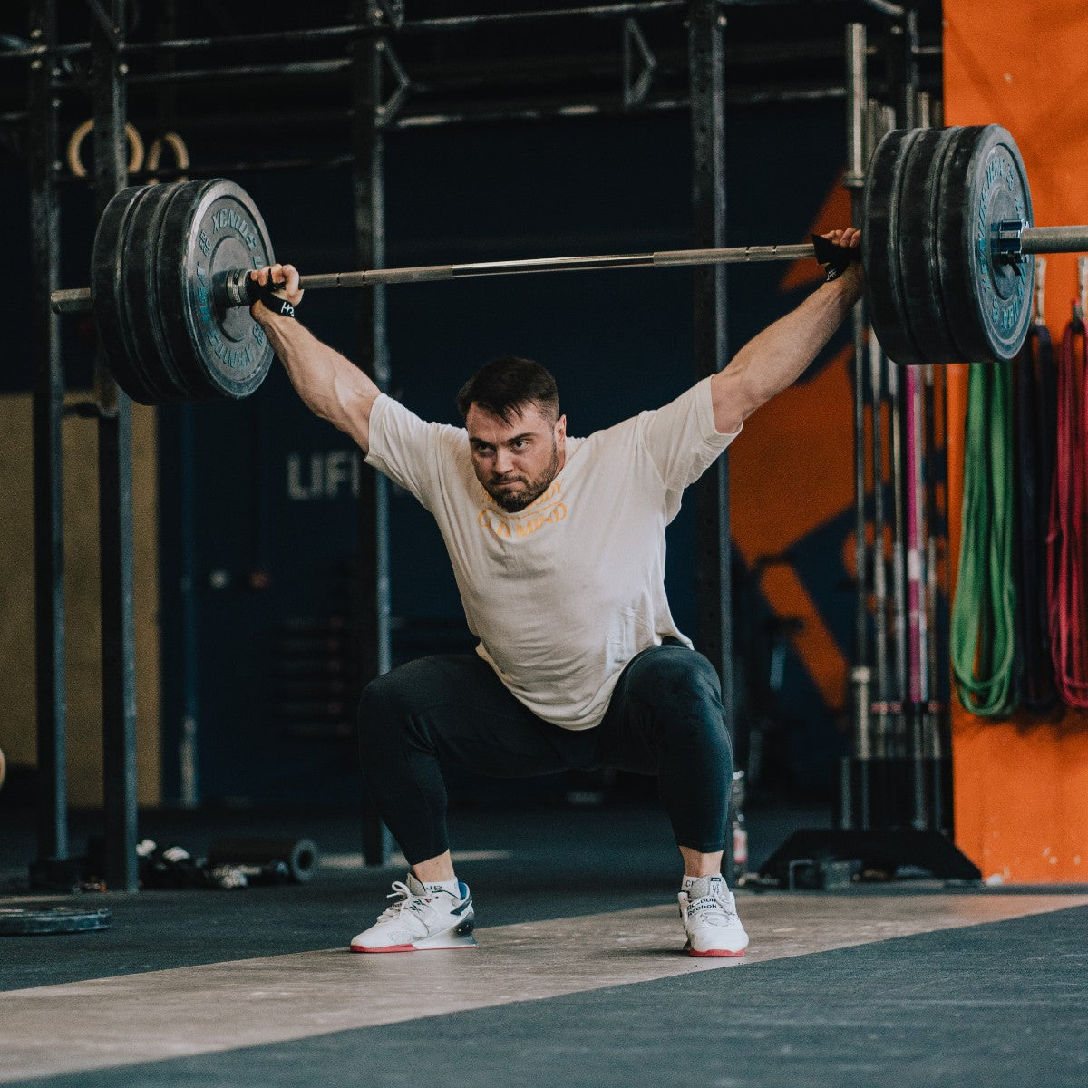 Oleksiy Torokhtiy lifting a barbell with weights in a gym setting, performing a squat exercise